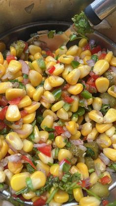 a pan filled with corn and vegetables on top of a stove