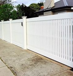 a white picket fence on the side of a house with grass in front of it