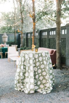 a table with a green and white cloth on it in the middle of a yard