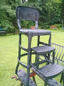 two black chairs sitting on top of a green field next to a metal park bench