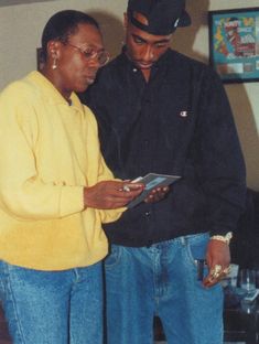 two men standing next to each other looking at something on a clipboard in their hands