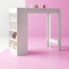 a white table with a cup on it in front of a book shelf and pink wall