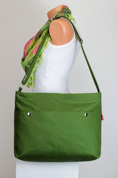 a green handbag is sitting on top of a mannequin's head