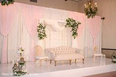 a white couch sitting on top of a wooden floor next to a wall covered in pink drapes