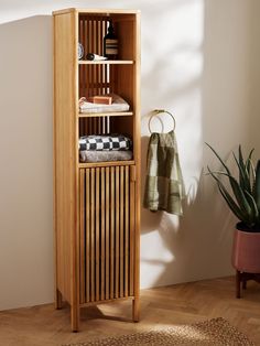 a wooden cabinet sitting next to a potted plant on top of a hard wood floor