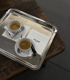 two cups of coffee sitting on top of a wooden table