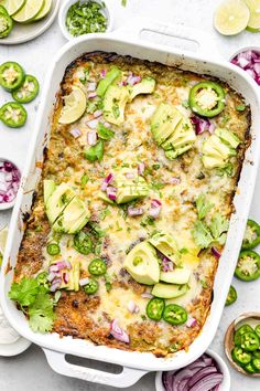 an enchilada casserole in a white dish with sliced jalapenos on the side