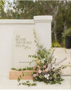 flowers and greenery are on the ground next to a sign that says, all because two people fell in love