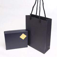 a black shopping bag with a yellow sticker on the side and a black gift bag next to it