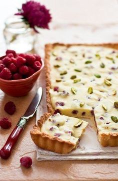 raspberry and pistachio tart with two slices cut out on a cutting board