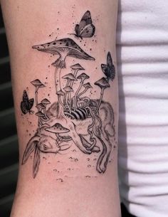 a woman's arm with an animal and mushrooms tattoo on the left side of her body