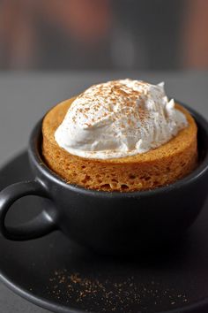 there is a small cup with whipped cream in it on the black plate and saucer