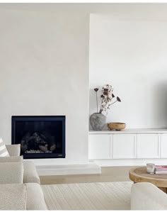 a living room with white furniture and a flat screen tv mounted on the wall above a fireplace