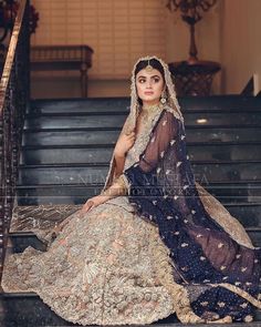 a woman sitting on some stairs wearing a dress and headpiece with an elaborate veil