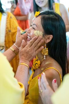 a woman is getting her face painted in yellow