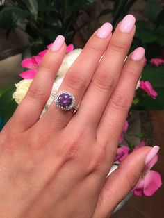 a woman's hand with pink manicured nails and a ring