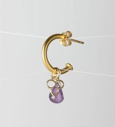 a pair of gold hoop earrings with an amethorate stone hanging from it