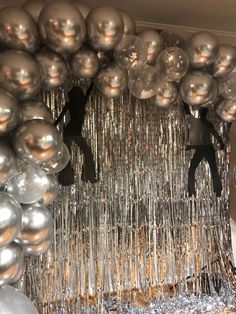 silver balloons and streamers hanging from the ceiling in front of a mirror ball backdrop