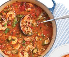 a pot filled with shrimp and vegetable soup next to another bowl full of food on a table