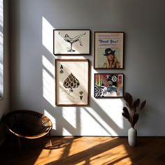 three framed pictures hang on the wall next to a chair and a potted plant