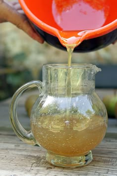 a pitcher filled with liquid being poured into it on top of an apple cider