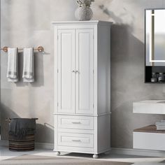 a bathroom with a white cabinet, mirror and towels on the wall next to it