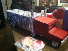 a cart made out of cardboard boxes sitting on top of a table next to other items