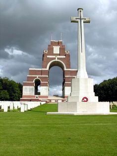 an obelisk in the middle of a grassy area with a cross on top