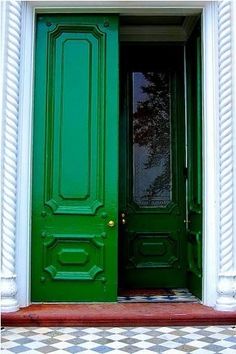 a green door with two white columns and a checkered floor