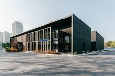 an empty parking lot in front of a large building with glass windows on the side