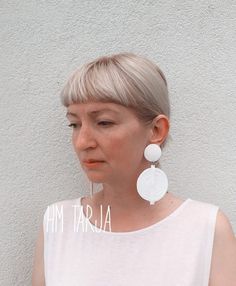 a woman with short hair wearing white earrings and a t - shirt that says am taraja