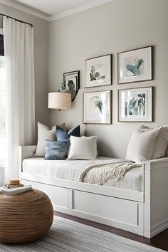 a white daybed with pillows and pictures on the wall above it in front of a window