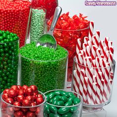 many different colored candies in glass containers with spoons and candy canes next to each other