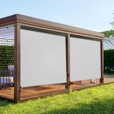 an outdoor covered patio area with sliding doors and privacy screens on the sides, surrounded by green grass