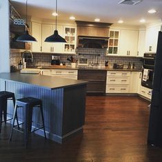 a kitchen with white cabinets and black bar stools