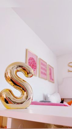 there is a gold sculpture on top of a white table in the room with pink walls