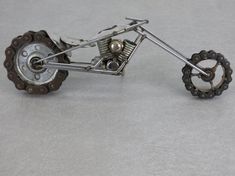 a metal model of a motorcycle with gears on the front and rear wheels, sitting on a gray surface