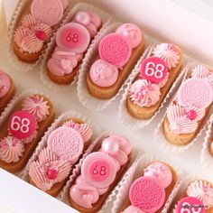 a box filled with pink decorated cookies in it's wrappers and numbers on them