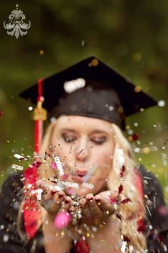 a woman wearing a graduation cap and gown throwing confetti in the air with her hands