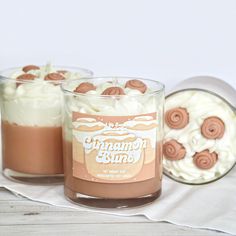 two jars filled with whipped cream and cinnamon buns on top of a white table