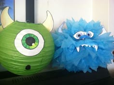 two green and blue paper lanterns with monster faces on them, one has big eyes