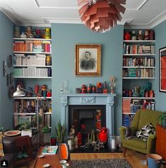 a living room filled with furniture and bookshelves next to a fire place under a chandelier