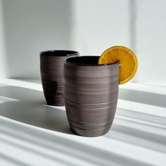 two gray cups with an orange slice in the middle and one on the other side