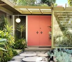 a pink door is in the middle of a garden with rocks and plants around it