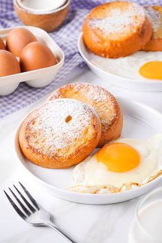 two plates with eggs and pastries on them