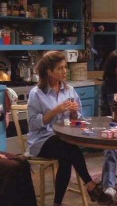 two women sitting at a table talking to each other in a kitchen with blue cabinets