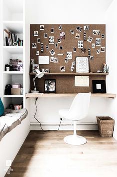 a white chair sitting in front of a desk with a cork board on the wall