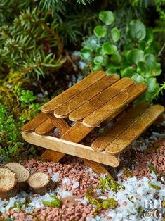 a wooden bench sitting on top of a pile of dirt next to trees and plants