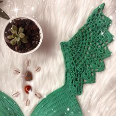 a crocheted green bikinisuit next to a potted succulent plant