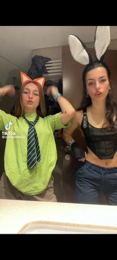 two girls in bunny ears and green shirts are posing for the camera with their hands behind their backs